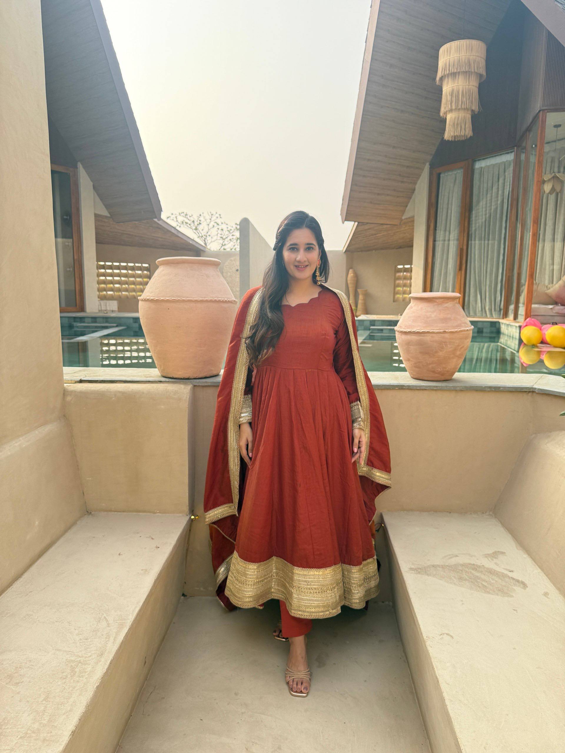 Regal Rust Orange Flared Anarkali Suit Set Featuring Ornate Gold Sequined Borders, a Scalloped Neckline, and an Elegant Tie-Up Back